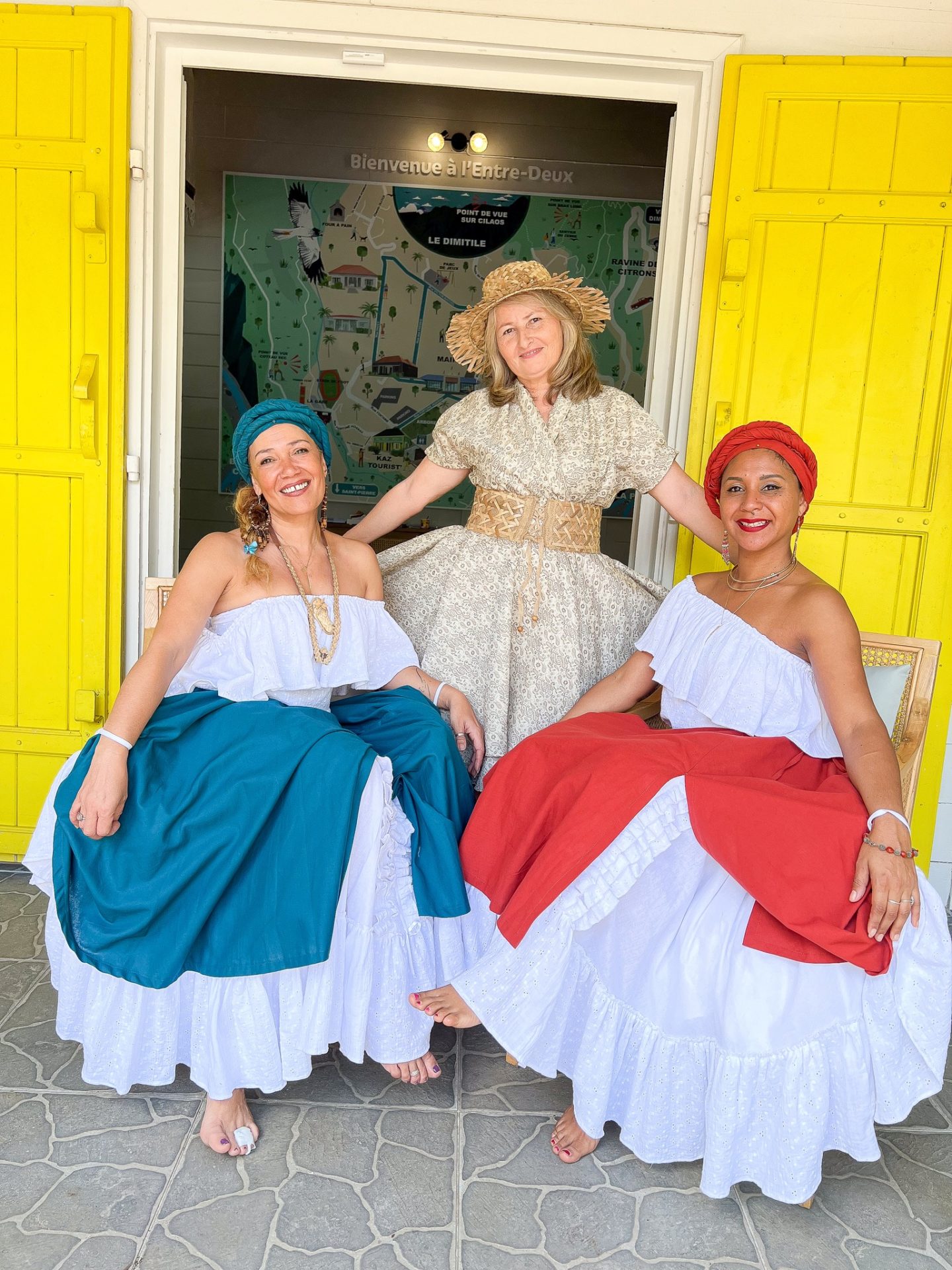 3 membres de l'équipe de l'OTI sud posent devant la kaz tourist. Les 3 personnes portent des robes traditionnelles créoles et sont souriantes